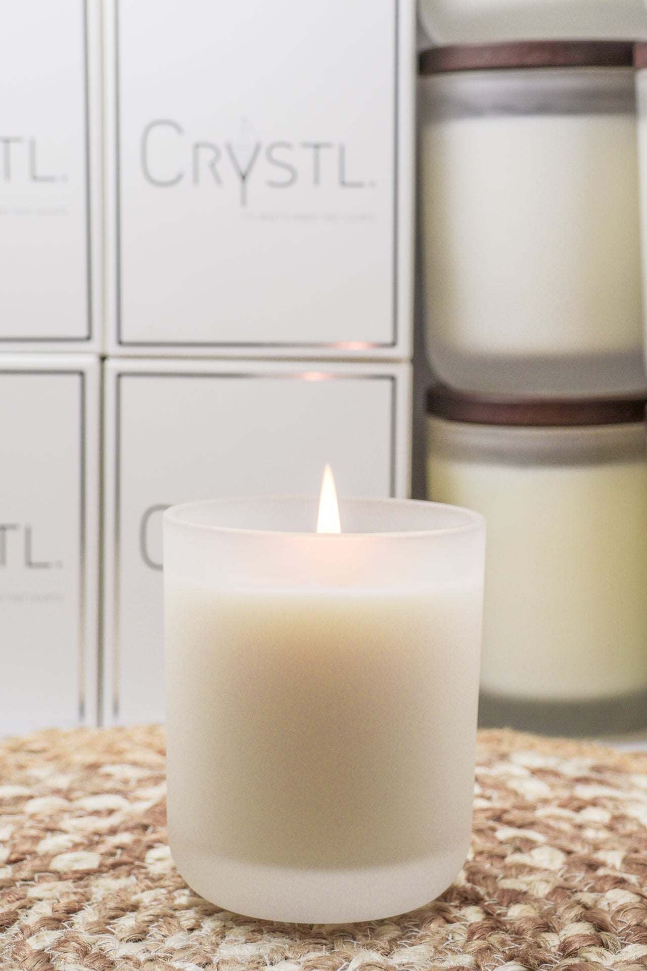 Crystal infused candle on a bench top with Crystl. Candle boxes behind